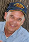 Tim Tingle headshot. Tim, a light-skinned indigenous man, wears a baseball cap and denim button-up shirt.