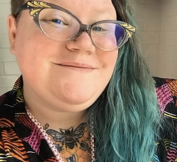 Photo of illustrator Theo Nicole Lorenz, smiling at the camera.
